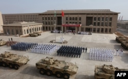 中国人民解放军人员参加吉布提中国军事基地开幕式。 这是中国第一个海外海军基地,是中国扩大其国外军事存在的重要一步(2017年8月1日)。地缘情报分析公司斯特拉福(Strarfor)的在线刊物“斯特拉福世界观”(Stratfor Worldview)和卫星图像分析公司“全资源分析”(Allsource Analysis)提供的两张图像显示,中国在吉布提的基地有三层安全防御,戒备森严。斯特拉福公司分析,这处基地有大约23000平方米的地下空间。该基地距离美军在吉布提的驻军总部只有八英里远,美国在吉布提的驻军有4500人。此外,日本、法国、英国等国在吉布提也有驻军。