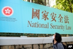 香港一名妇女走过街头的国安法宣传牌。(2020年6月30日)
