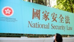 香港一名妇女走过街头的国安法宣传牌(美联社2020年6月30日)