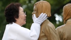 在韩国首尔,二战期间被迫成为日军性奴的李永洙在一尊象征战时“慰安妇”的少女雕像揭幕仪式上触摸雕像的脸。(2019年8月14日)