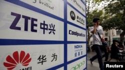 一名中国男子从武汉街头有着华为和中兴标徽的广告牌前走过。(资料照片)