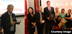 左图:重病康复中的“中国法律界良知”张思之致颁奖辞。右图:2014年度公和人物颁奖典礼会主持人耿潇男女士(左一)与她称为“圣徒”而鼎力推荐的卢百可先生,与张思之先生(左二)共同为卢百可颁奖。(左三)卢百可带他的四个女儿与颁奖人在颁奖台合影,手持木刻画像由独立学人毛喻源雕刻(耿潇男拍摄)