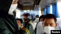一名中国医务人员在高速公路上的检查站为一名长途客车上的旅客量体温。(2003年5月10日)
