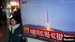 2016年2月7日,韩国首尔火车站,一位旅客走过正在显示北朝鲜发射远程火箭新闻的电视屏幕。