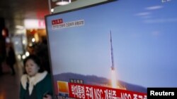 2016年2月7日,韩国首尔火车站,一位旅客走过正在显示北朝鲜发射远程火箭新闻的电视屏幕。