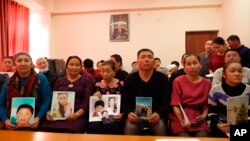 在哈萨克斯坦阿拉木图一个中国哈萨克族人组织的办公室里,人们手举在新疆失踪亲属的照片。(2018年12月7日)