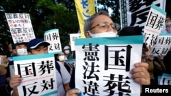 日本部分民众站在街头,手举反对给予日本前首相安倍晋三国葬待遇的标牌。 -路透社资料照