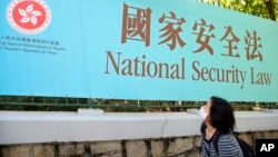 香港一名妇女走过街头的国安法宣传牌。(2020年6月30日)