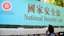 香港一名妇女走过街头的国安法宣传牌。(2020年6月30日)