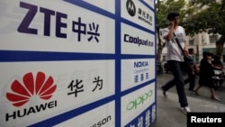 一名中国男子从武汉街头有着华为和中兴标徽的广告牌前走过。(资料照片)