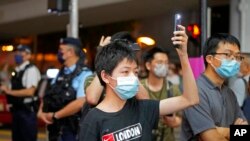 2022 年 6 月 4 日星期六,支持民主的抗议者在香港维多利亚公园附近手持发光的手机。