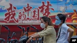 骑着电动车的中国女子驶过中国梦的宣传画。(2022年6月20日)