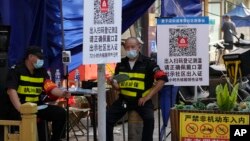 北京街头两名保安把守需要扫健康码和社区出入证方能出入的社区入口。(2022年6月20日)