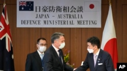澳大利亚国防部长马勒斯和日本防务大臣岸信夫在东京举行联合记者会后握手。(2022年6月15日)