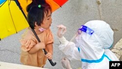 中国安徽省泗县的医护人员在给一名女童做新冠核酸检测。(2022年7月4日)