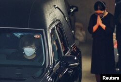 安倍晋三的遗孀昭惠坐在安倍的灵车前座开往寺庙。(2022年7月11日)