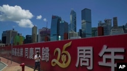 一名男子走过香港街头竖立的庆祝香港主权回归中国的标语。(2022年6月23日)