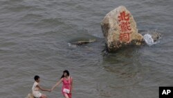 资料照 - 2008年8月8号,一位妇女和一名孩子在河北省秦皇岛北戴河的海滩上游玩。