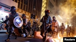 资料照:香港防暴警察走过一个燃烧的路障去驱散抗议民众。(2019年11月2日)