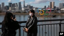 一名戴口罩的游客在东京拍照,背景是奥林匹克运动会标志。2020年1月29日照片