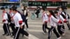 带着口罩的北京小学生穿过一条交通繁忙的十字路口。(美联社照片 2021年4月29日)