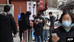 2021年1月14日人们在北京一家医院排队测试新冠病毒时通过手机刷健康码。(法新社提供)