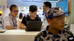 在全球移动互联网大会上,一名与会者在会议保安身后使用电脑