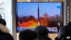 2022 年1月6日,在韩国首尔火车站的新闻节目中,人们在电视上观看显示朝鲜发射导弹图像的电视。(美联社)。