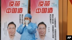 资料照:一名医护人员站在中国疫苗的广告前。(2021年4月9日)