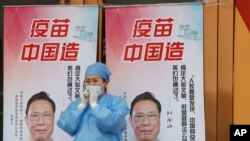 北京一位医护人员站在“疫苗中国造”宣传画前。(2021年4月9日)