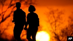 美国密苏里州堪萨斯城一对夫妇在公园中散步,夕阳余辉衬托出他们的剪影。美国疾控中心下属的国家健康统计中心周四(2022年12月22日)公布了最终确定的全国死亡率数据,美国人的平均寿命在2020年缩短了1.8年,在2021年缩短0.6年,两年合计缩短了2.5年,目前下降到76.4年。
