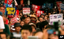 日本国会通过扩充军事力量的防卫法案后,抗议者在国会大厦前举行反战示威集会。