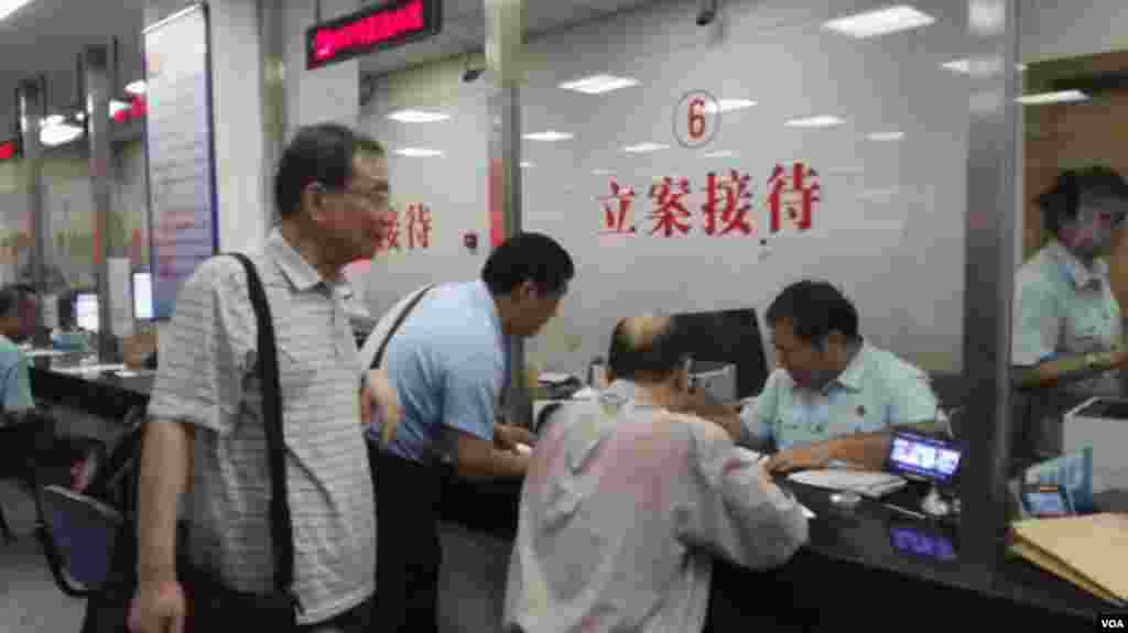 丁锡奎律师(窗口前坐者)受杜导正、胡德华和徐庆全委托在法院递交起诉材料。
