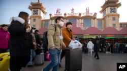 戴着口罩的旅客走在北京火车站外。(2020年1月20日)