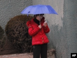 一名朝鲜女性在平壤一条人行道上使用手机。(资料图:2012年3月16日)