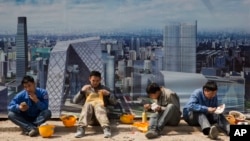 资料照:在北京中央商业区工地外围吃饭的中国建筑工人。
