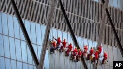 2018年8月31日,中国中央电视台(CCTV)总部大楼外面,悬挂在绳索上的工人擦玻璃。
