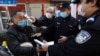 湖北武汉街头设立的检查卡社区工作人员检测行人的体温,警察检查其身份文件。(2020年2月20日)