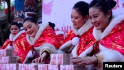 资料照片:在中国杭州一个公园里,工作人员在一场有奖游戏中摆放百元钞票(2016年1月26日)