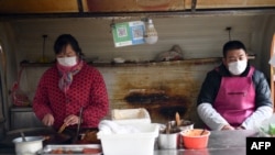 2020年1月26日,北京一家餐馆员工戴口罩进行食品操作。