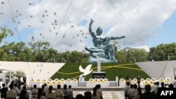 资料照:日本长崎民众在和平公园里和平祈愿像前纪念原子弹爆炸75周年。(2021年8月9日)