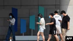 北京字节跳动总部大楼旁几个青年边走路边看手机。(2020年7月6日)
