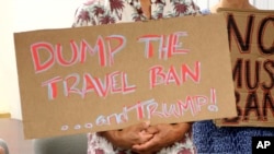 川普总统的批评者举着一块标语牌,呼吁撤销旅行禁令。(2017年6月30日)