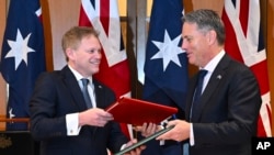 2024年3月21日,英国国防大臣格兰特·沙普斯(Grant Shapps,左)和澳大利亚国防部长理查德·马勒斯(Richard Marles)在澳大利亚议会交换新签署的国防和安全合作协议。
