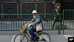 中国政府推出行政命令,削减工业落后产能,其中钢铁产能削减幅度最大。图为一名男子骑自行车穿过北京街头。