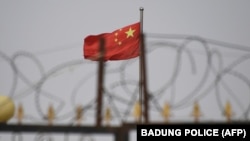 资料照:新疆喀什南部地区一处围着铁丝网的小区里飘扬着中国国旗。 (2019年6月4日)