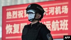 2020年4月8日武汉城市解封,天河国际机场内一名戴着口罩的警察站在标语牌前。