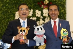 中国总理李克强和印度尼西亚总统佐科·维多多在印尼总统府分享轻松时刻,手持2018年亚运会的吉祥物。(2018年5月7日)