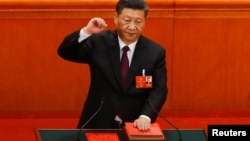 中国国家主席习近平在连任第二个任期时左手抚按宪法,右手举拳,宣誓就任。(2018年3月17日)