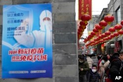 资料照:北京街头一幅接种新冠疫苗的宣传画。(2021年2月14日)